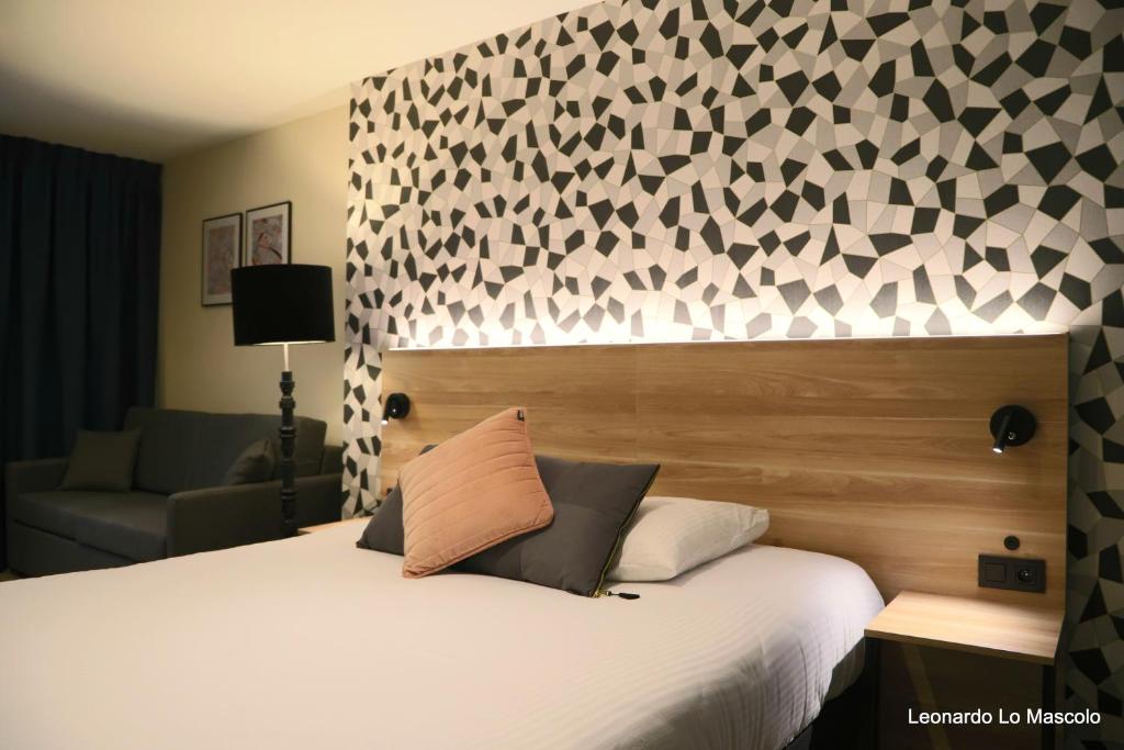 a bedroom with a large bed with a white bedspread and a wall at Hôtel de l'Univers Liège in Liège