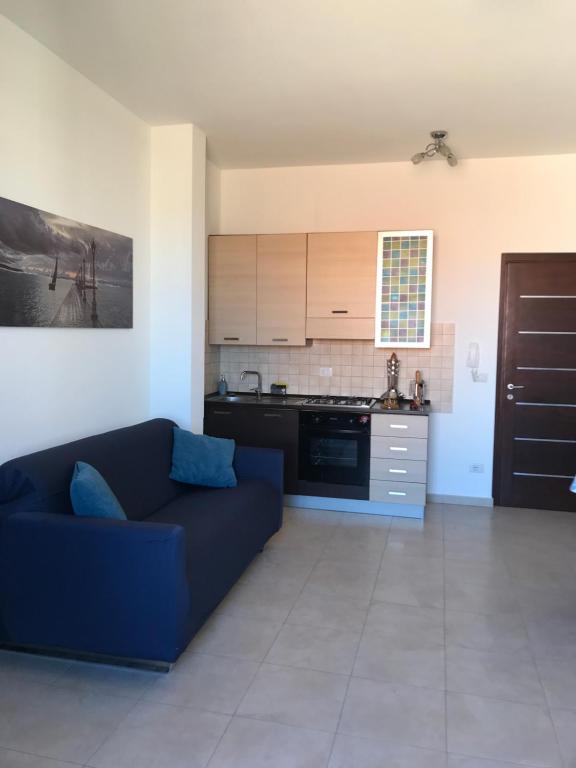 ein Wohnzimmer mit einem blauen Sofa und einer Küche in der Unterkunft Alghero Appartamento la Corbata in Alghero