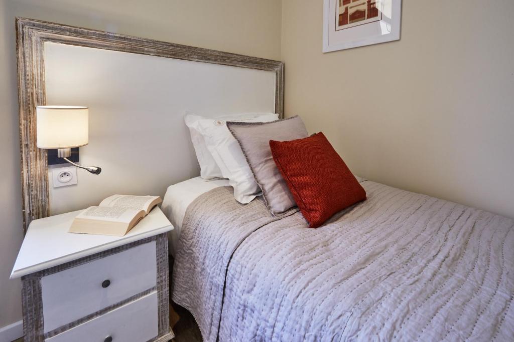 a bedroom with a bed with a red pillow and a nightstand at Les Villas d'Arromanches, Teritoria in Arromanches-les-Bains