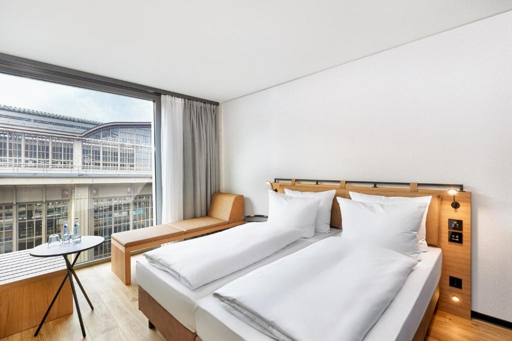 a bedroom with two beds and a large window at H2 Hotel Leipzig in Leipzig