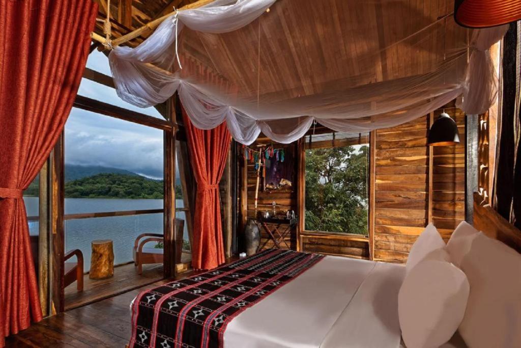 a bedroom with a bed and a large window at Lak Tented Camp in Lien Son