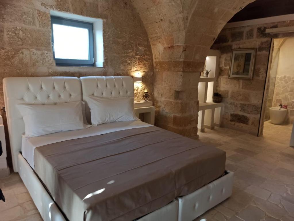 a bedroom with a white bed in a stone room at Mascava di Torre Guaceto in Brindisi