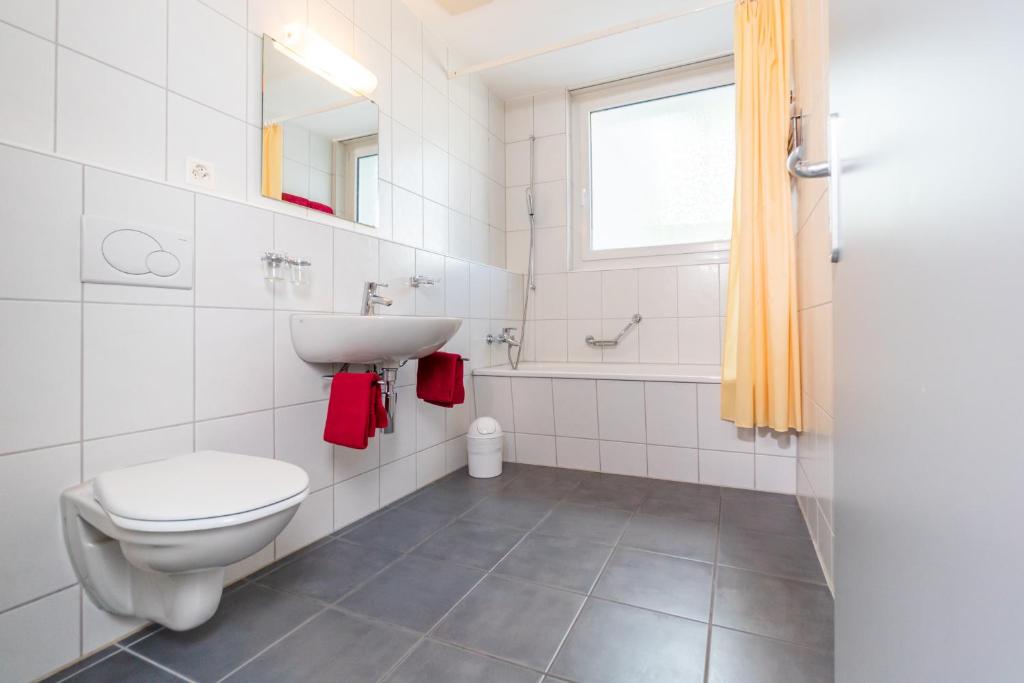 La salle de bains blanche est pourvue d'un lavabo et de toilettes. dans l'établissement Face Aparthotel, à Davos