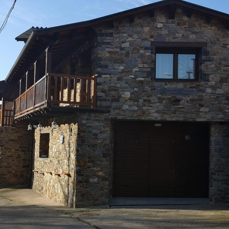 a brick building with a garage and a balcony at Casa Rural Rio Cabrera in Las Médulas