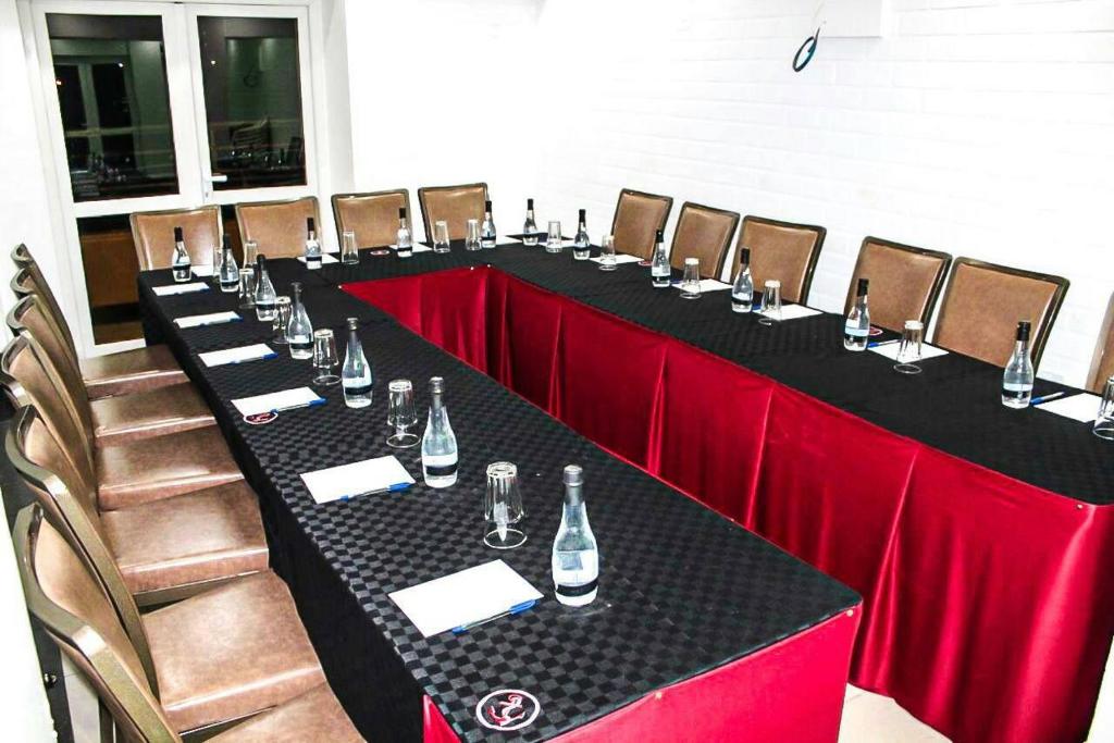 una mesa larga con cortinas rojas y botellas de vino en Anchor Hotel, en Nairobi