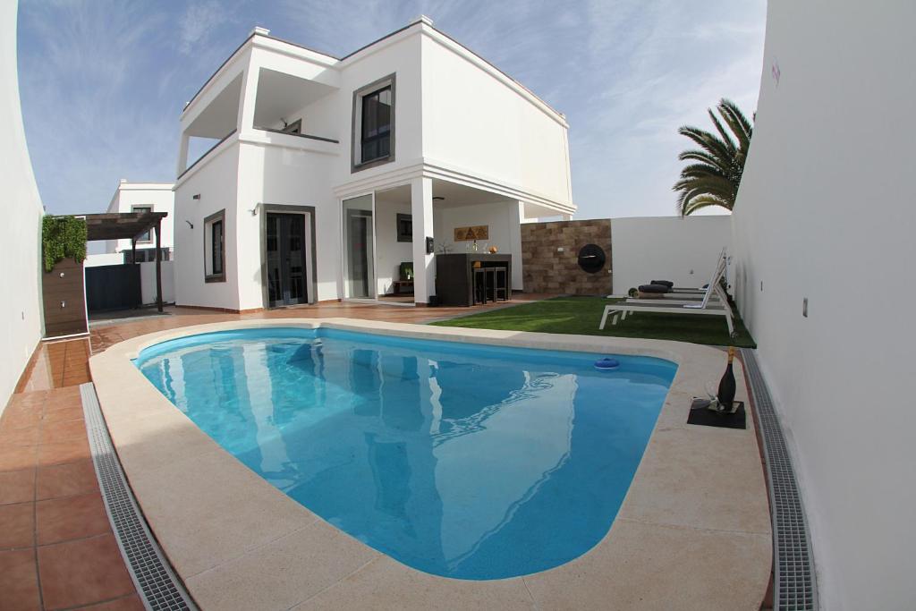 a villa with a swimming pool in front of a house at Villa Garoed in Playa Blanca