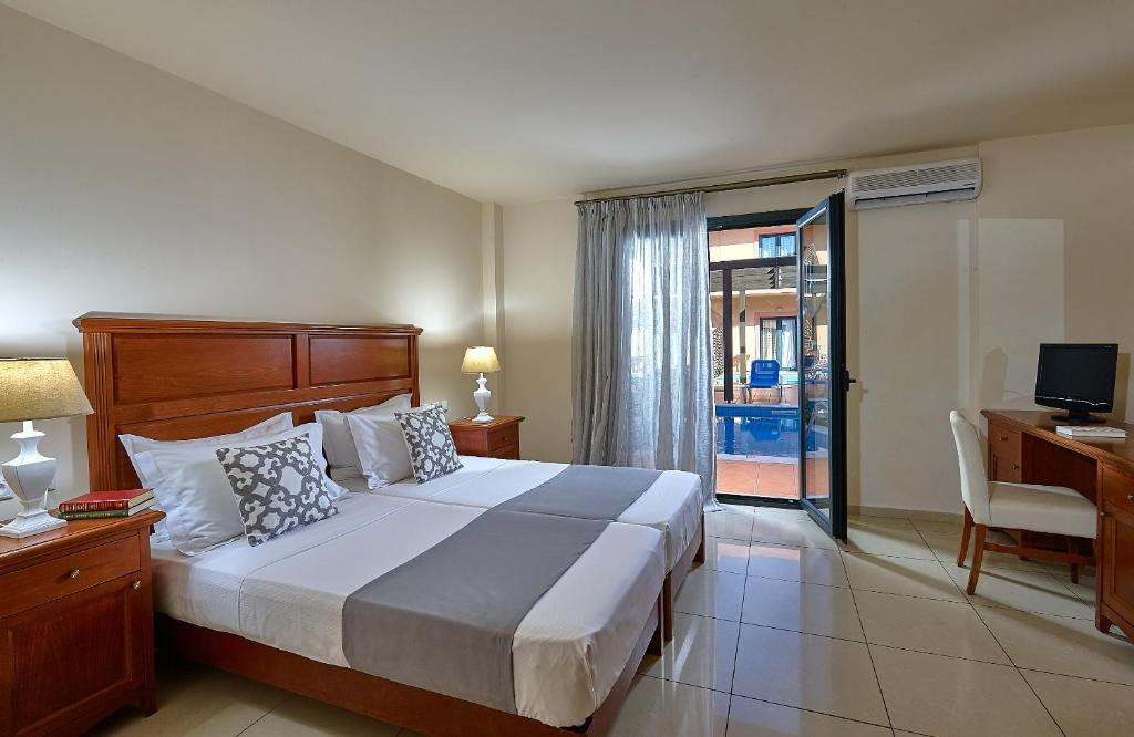 a bedroom with a bed and a desk and a television at Vasia Resort & Spa in Sisi