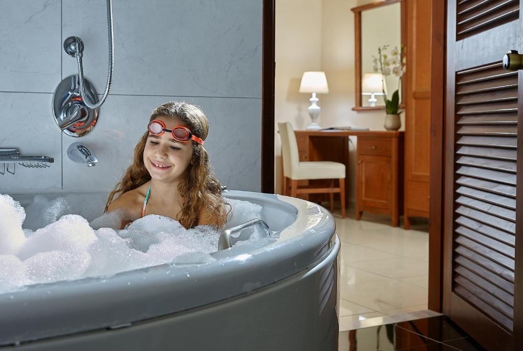 a young girl in a bathtub with sunglasses on her head at Vasia Resort & Spa in Sisi