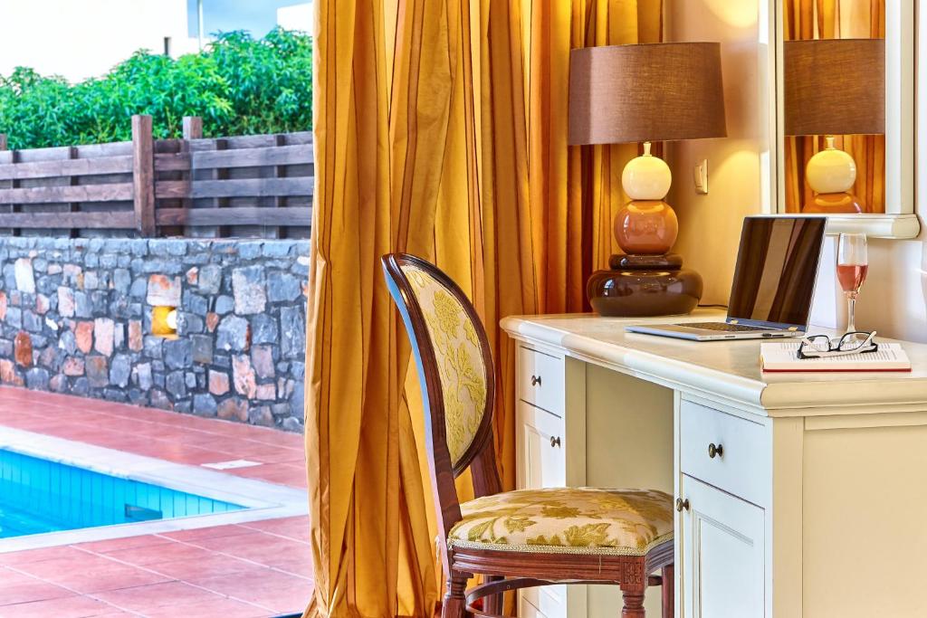 a desk with a computer and a chair next to a window at Vasia Resort & Spa in Sisi