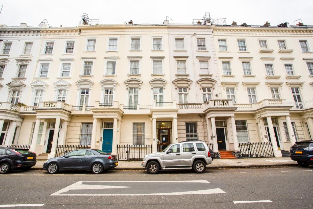 Un gran edificio blanco con coches aparcados delante. en St George's Hotel, en Londres