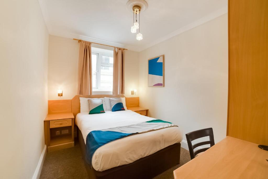 Schlafzimmer mit einem Bett, einem Tisch und einem Fenster in der Unterkunft The Gullivers Hotel in Brighton & Hove