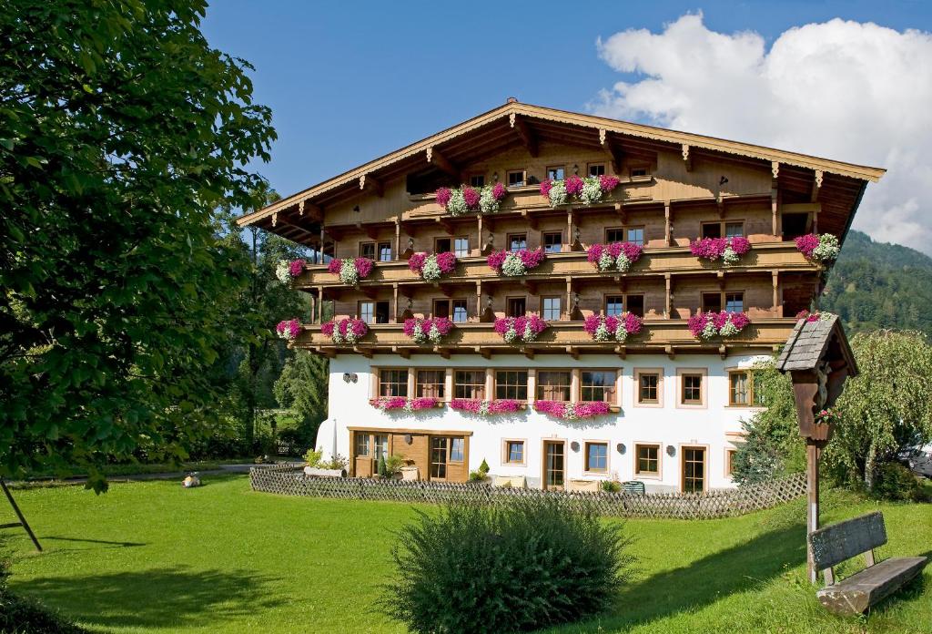 ein großes Gebäude mit Blumen auf den Balkonen in der Unterkunft Hotel Gut Kramerhof in Kirchdorf in Tirol