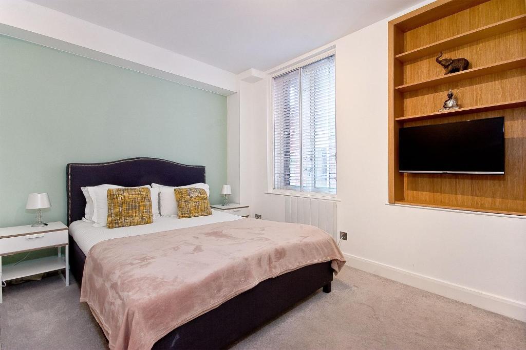a bedroom with a bed and a flat screen tv at Mulberry Flat 1 - One bedroom 1st floor by City Living London in London