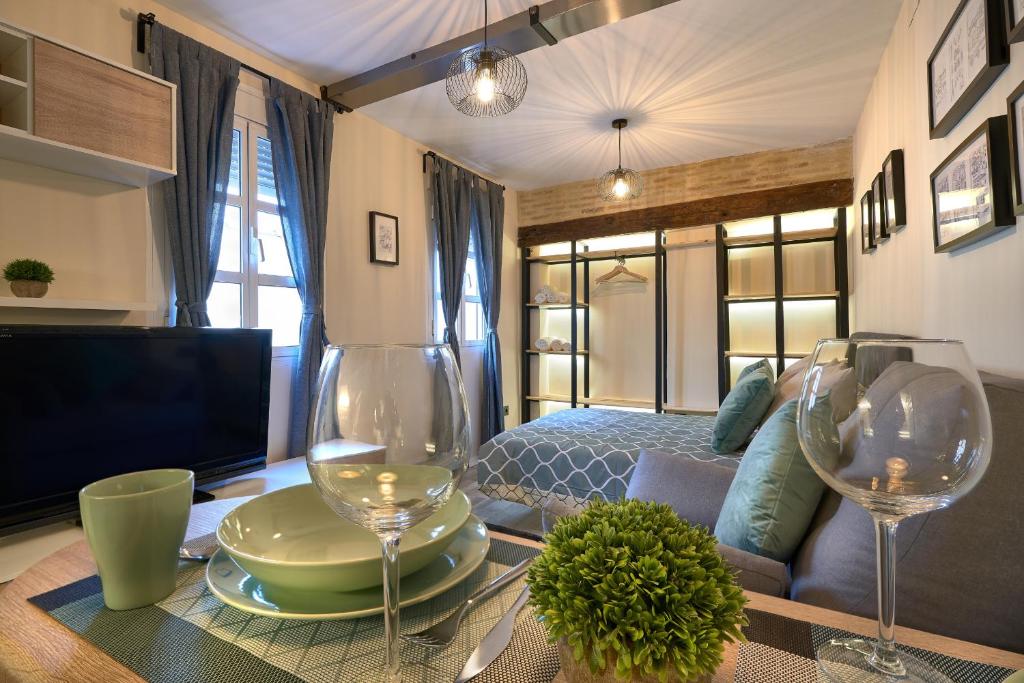 salon z łóżkiem i kieliszkami do wina na stole w obiekcie Loft en Triana w Sewilli