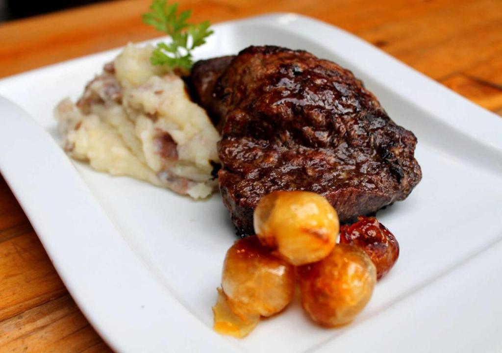 a white plate with a piece of meat and potatoes at Hotel Punta Sirena in Curanipe