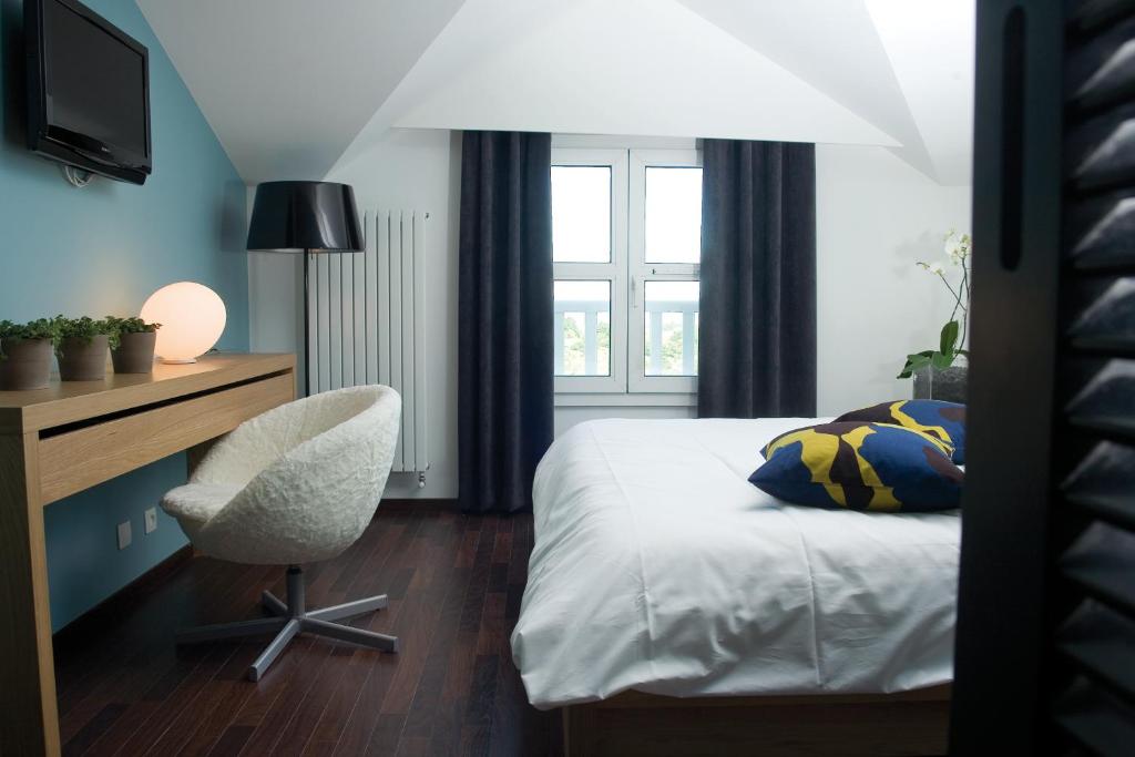 a bedroom with a bed and a desk and a chair at Hotel Du Golf in Saint-Étienne