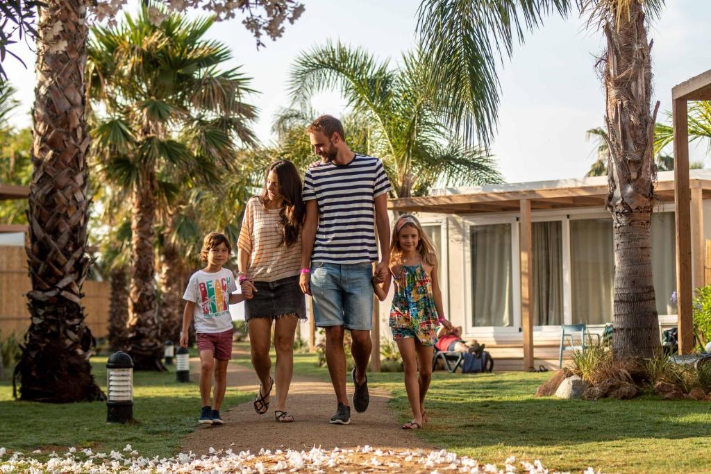 Ein Mann und seine Familie gehen durch einen Park. in der Unterkunft Alannia Els Prats in Mont-roig del Camp