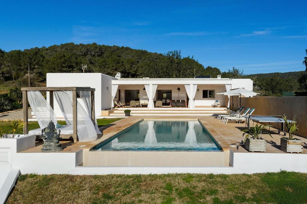 una villa con piscina di fronte a una casa di Villa Can Vinyes a Santa Gertrudis de Fruitera