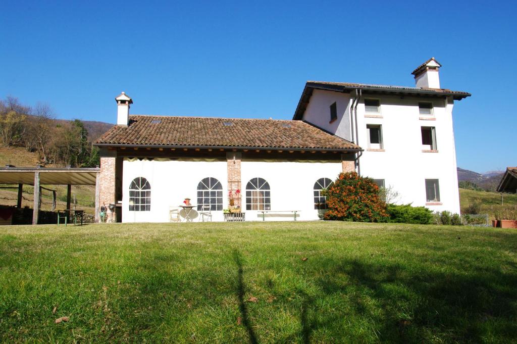 a large white house with a grass field in front of it at Agriturismo Corte del Maso in Bassano del Grappa