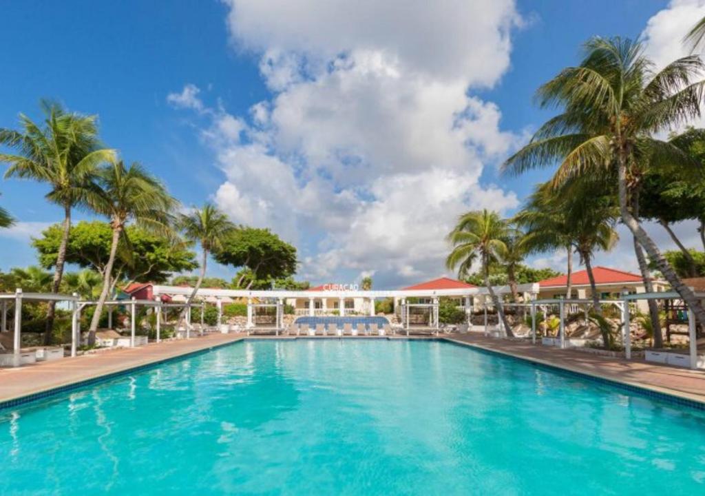 a pool at a resort with palm trees at Apartamento Familiar Vacaciones en Curacao in Jan Thiel