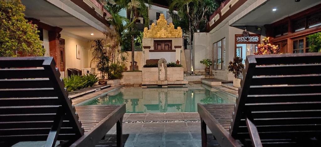 a swimming pool with a fountain in a building at Hana Kuta Beach Hotel in Kuta