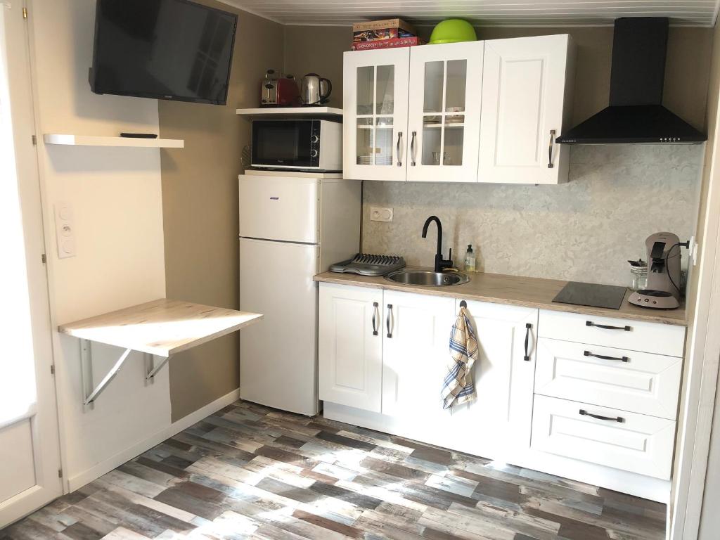 uma cozinha com armários brancos e um lavatório em studio 2 étoiles em Mimizan