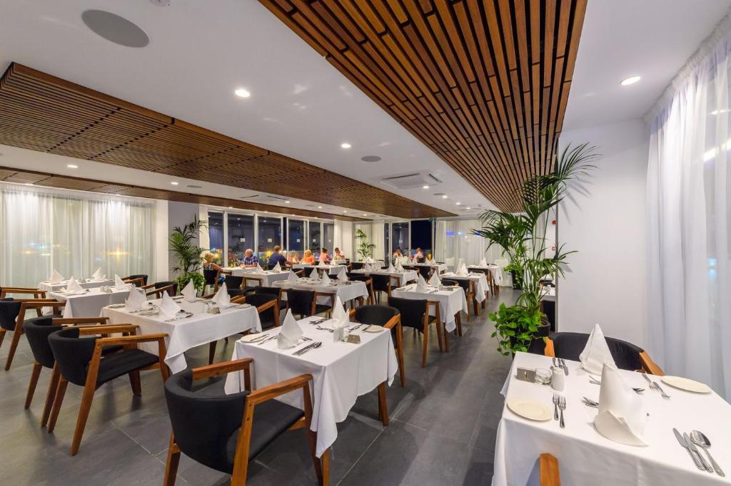 a dining room with white tables and chairs at Tasia Maris Beach Hotel - Adults Only in Ayia Napa