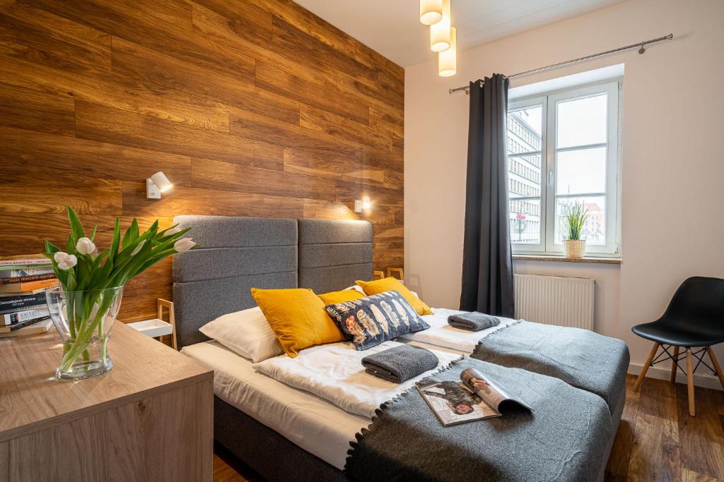 een slaapkamer met een bed en een houten muur bij Solny Square Aparthotel in Wrocław