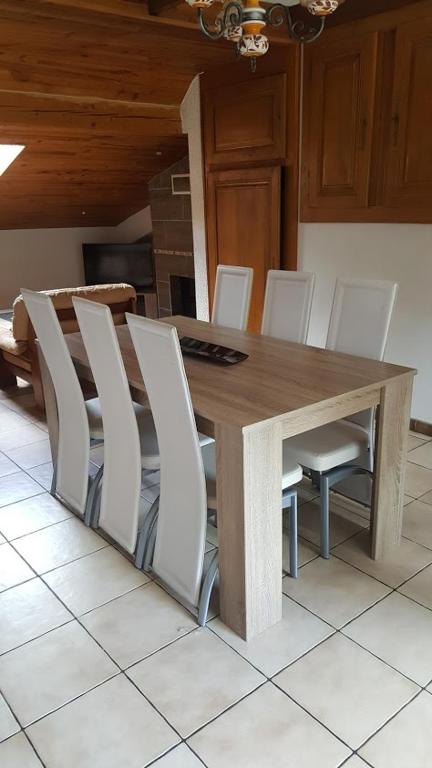 une table de salle à manger avec des chaises blanches autour dans l'établissement Le repaire du deux roues, à Saint-Sauveur