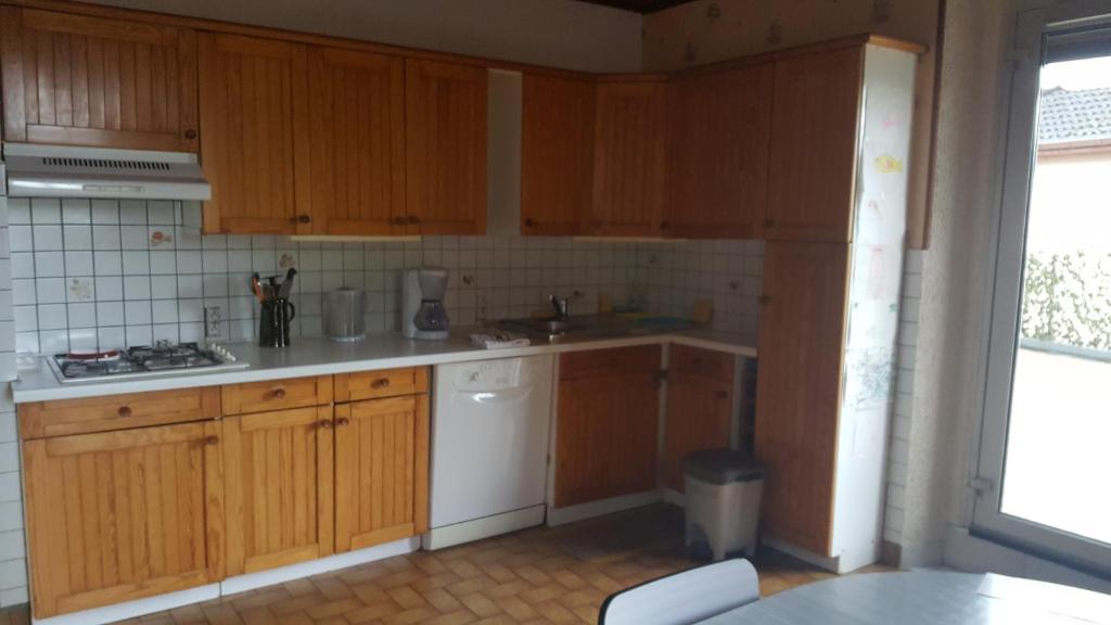 a kitchen with wooden cabinets and a white appliance at Le repaire du deux roues in Saint-Sauveur