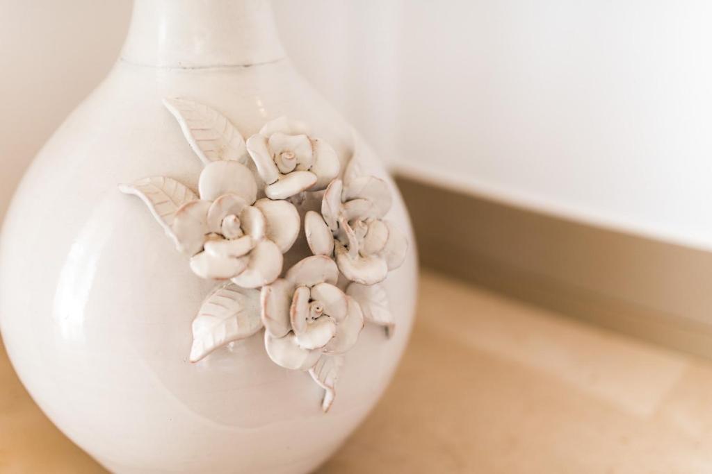 a white vase with flowers in it on a table at Punto Verde in Noci