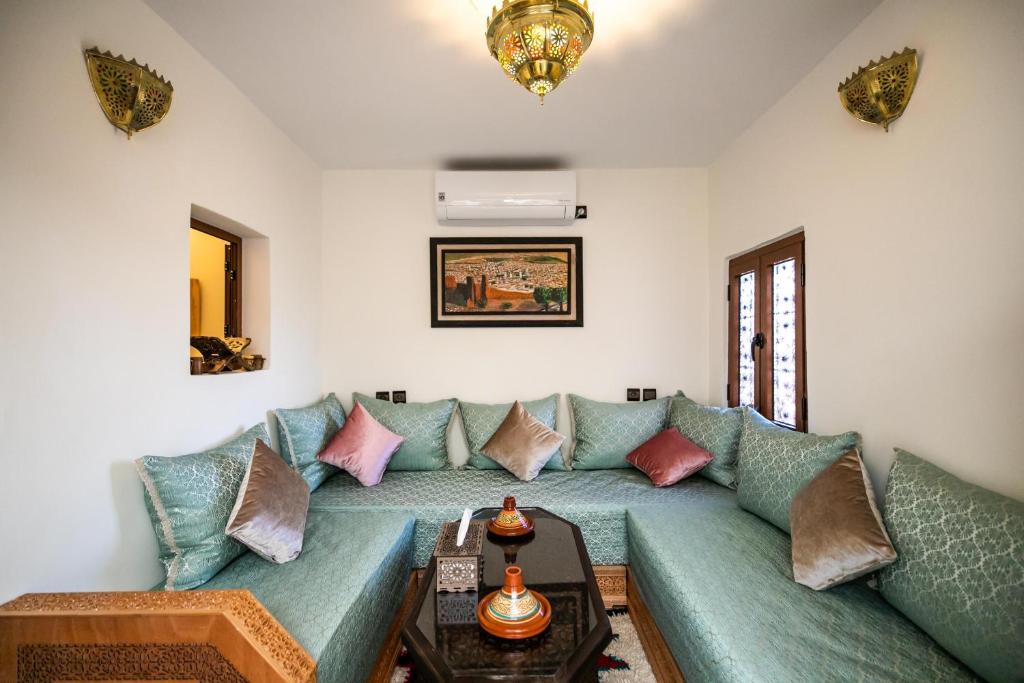 una sala de estar con un sofá verde con almohadas en Apartment Lala Rkia, en Fez