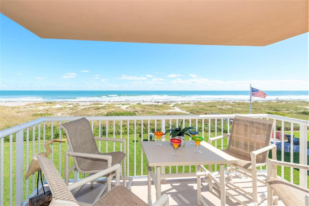a table and chairs on a balcony with the beach at Spanish Main in Cocoa Beach