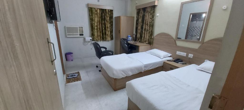 a hotel room with two beds and a mirror at Hotel Fortune in Patna