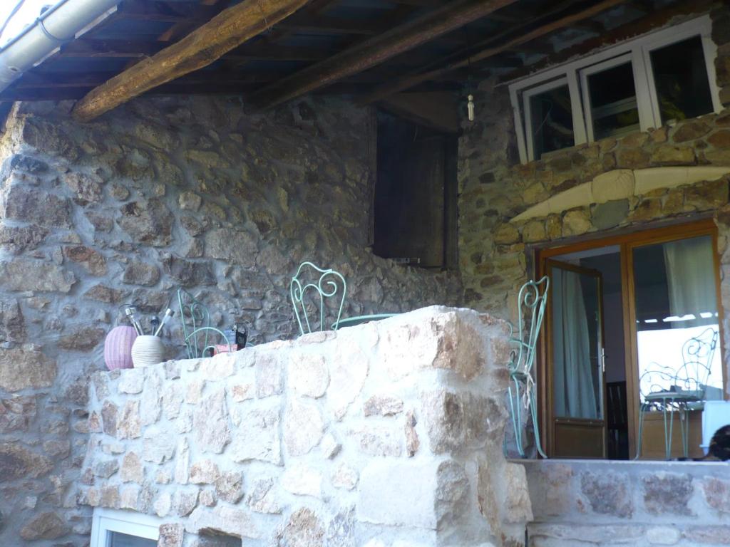 a stone house with a stone wall and a window at gite Sous le Figuier in Vals-les-Bains
