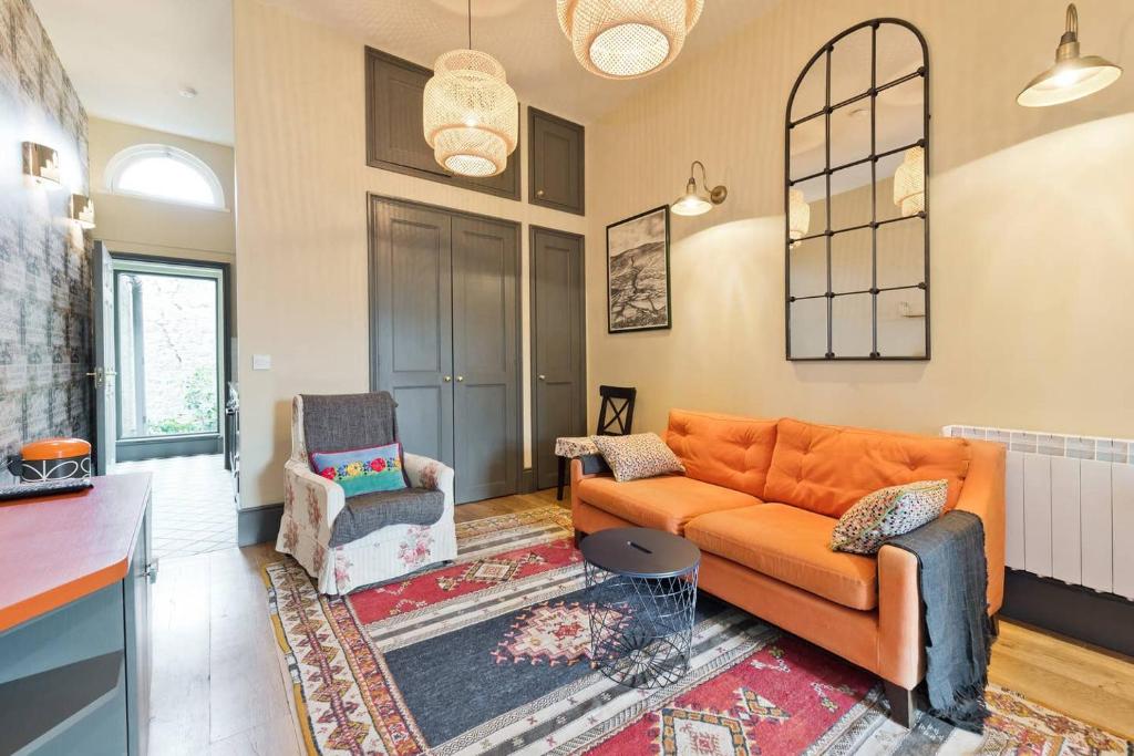 a living room with an orange couch and a chair at The Manor Suite at Moyglare House in Maynooth