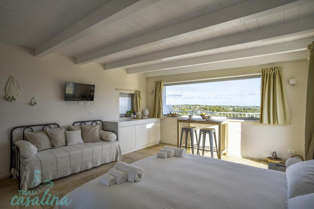 a living room with a white couch and a kitchen at Trulli Casalina in Cisternino