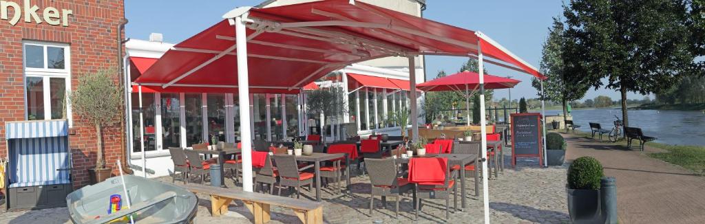 Hotel & Restaurant Gasthaus Zum Anker في Elster: مطعم بطاولات وكراسي تحت مظلة حمراء