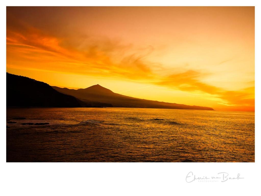 a sunset over a body of water with a mountain at Crepúsculo in Puerto de la Madera