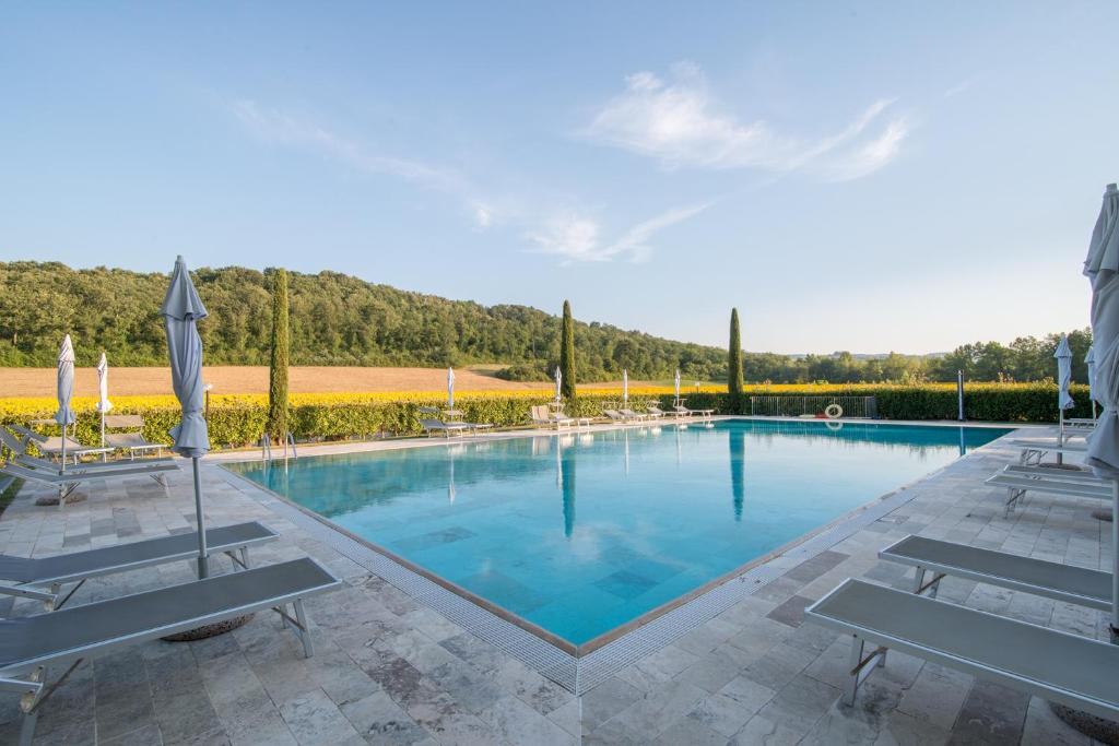 een groot zwembad met stoelen en parasols bij Steccaia Holiday Home in Villa del Monte