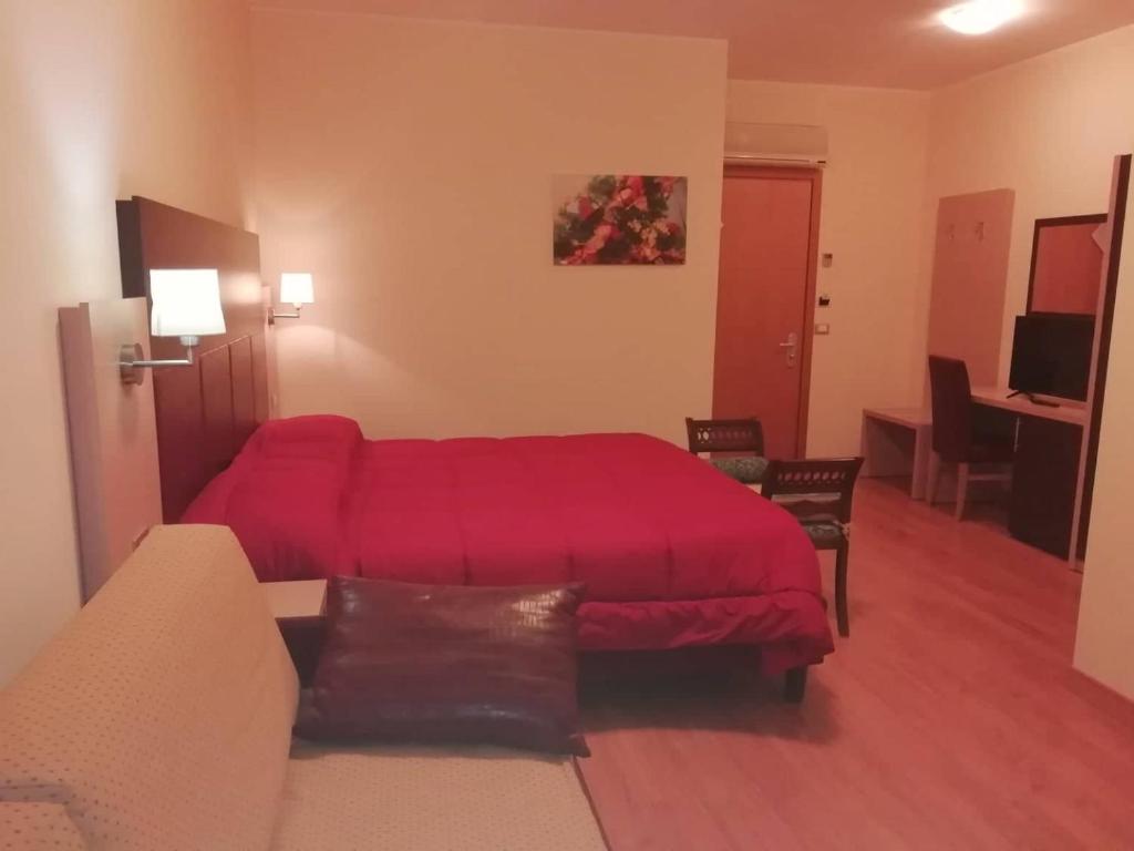 um quarto com uma cama vermelha e um sofá em Hotel Miami em Civitella del Tronto