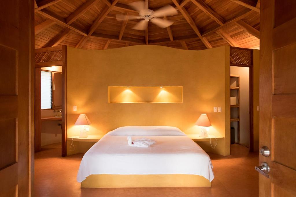 a bedroom with a white bed with two lamps at Hotel Playa Negra in Paraíso