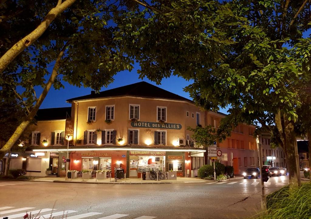 un bâtiment situé sur le côté d'une rue la nuit dans l'établissement Hôtel Des Alliés, à Pont-dʼAin