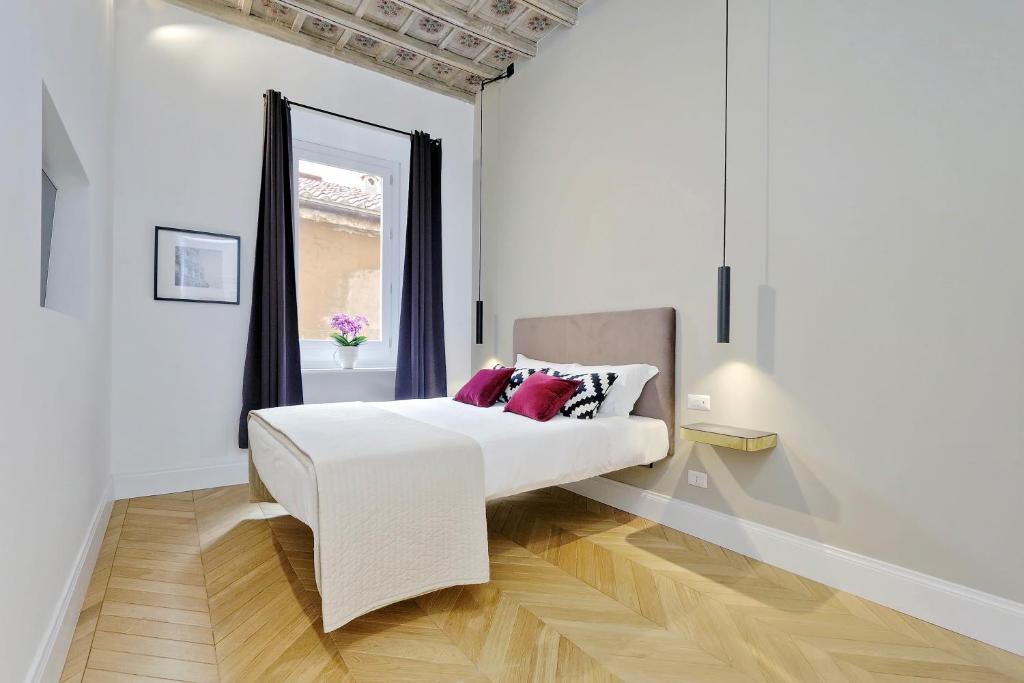Dormitorio blanco con cama con almohadas rojas en EVE Guest House at Trevi Fountain, en Roma