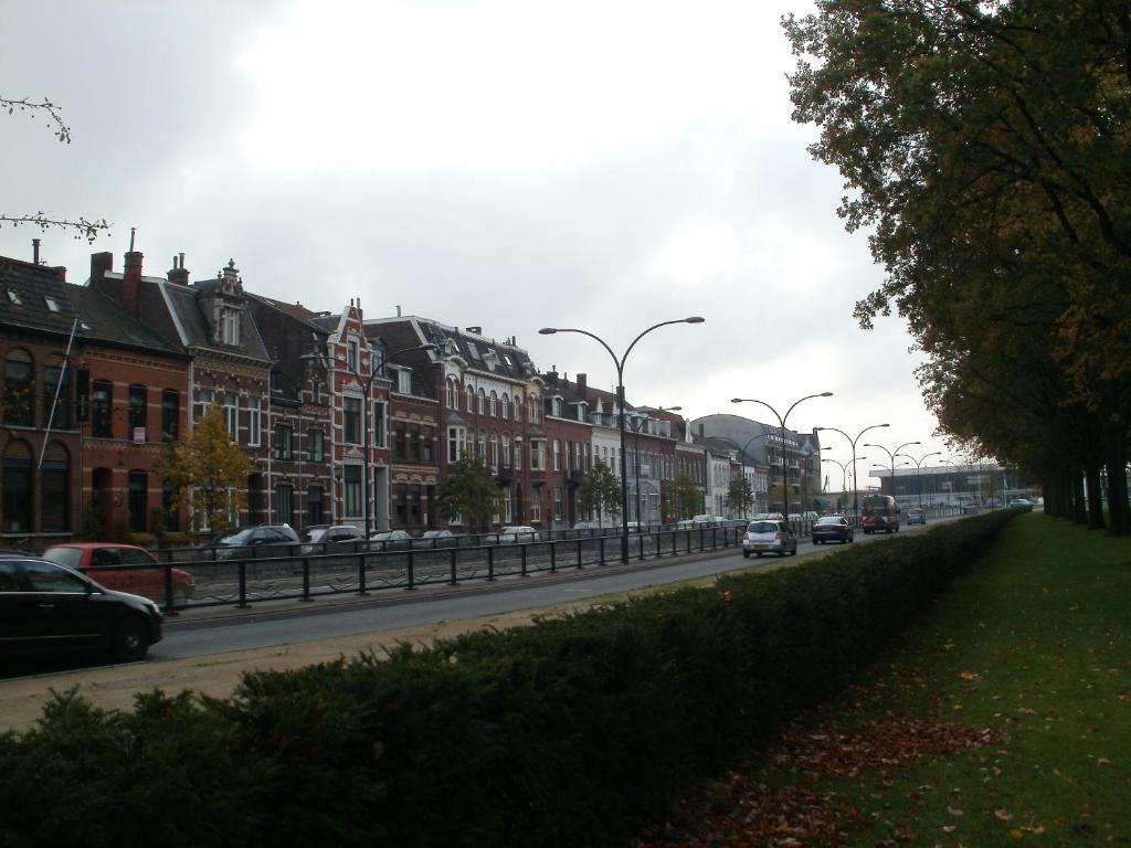 a street with cars driving down a street with buildings at Op de Burg in Venlo