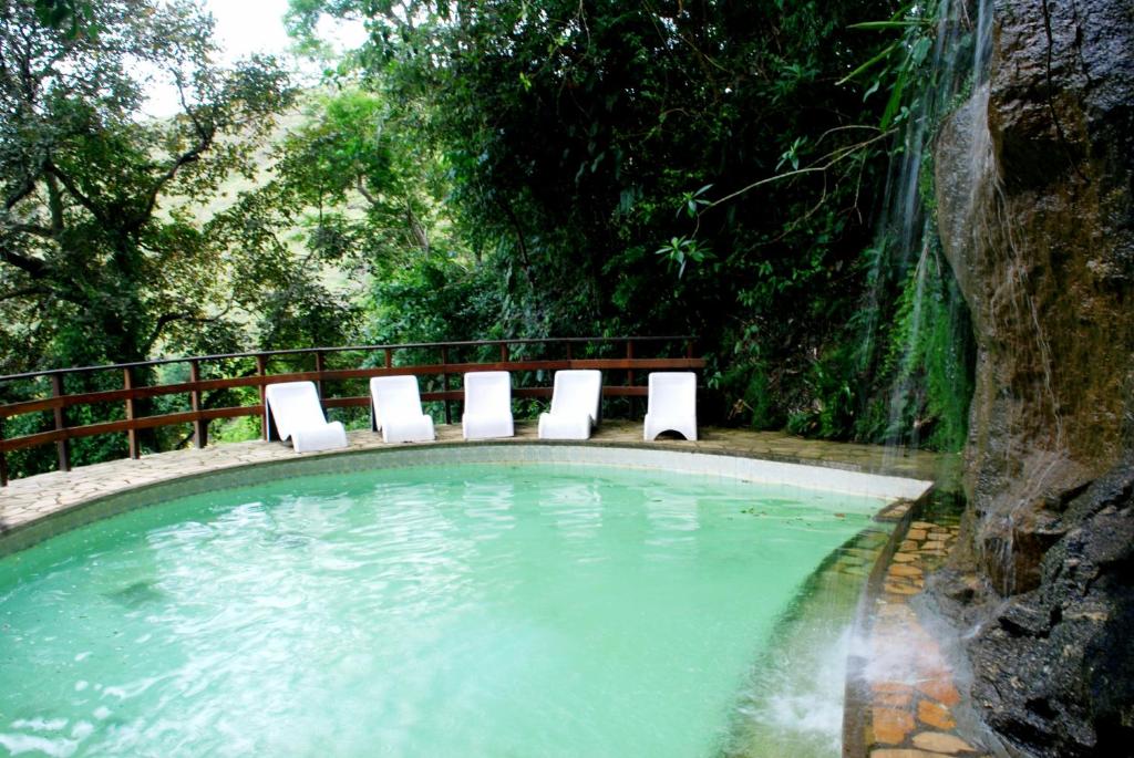 una piscina con sillas en el agua en Hotel Montanhes en Miguel Pereira