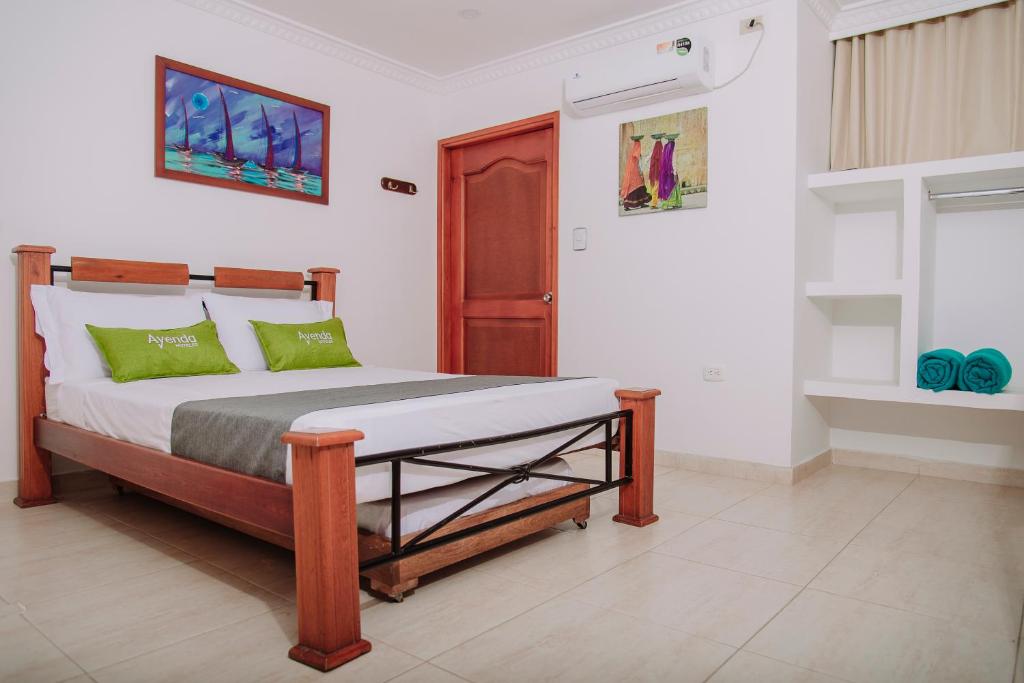 1 dormitorio con 1 cama con almohadas verdes en Ayenda 1618 Hotel Colon Rodadero, en Santa Marta