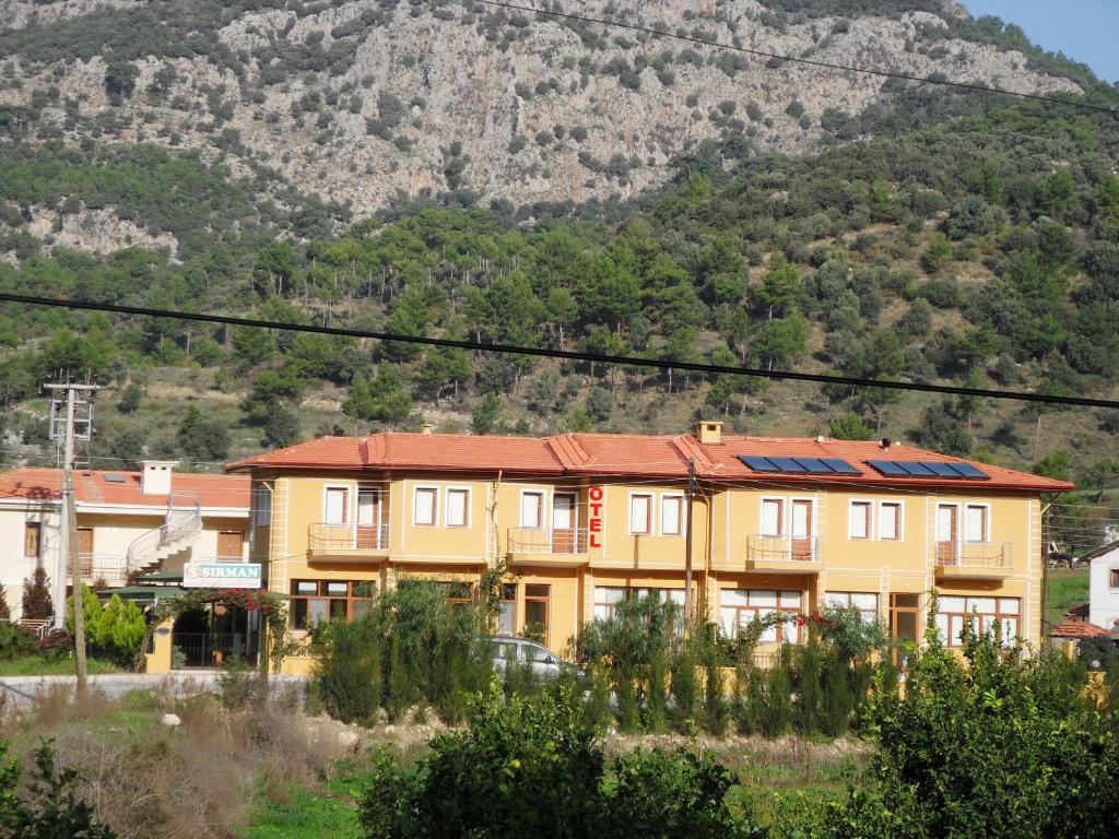 un edificio amarillo con una montaña en el fondo en Sirman Apart Hotel, en Sarigerme