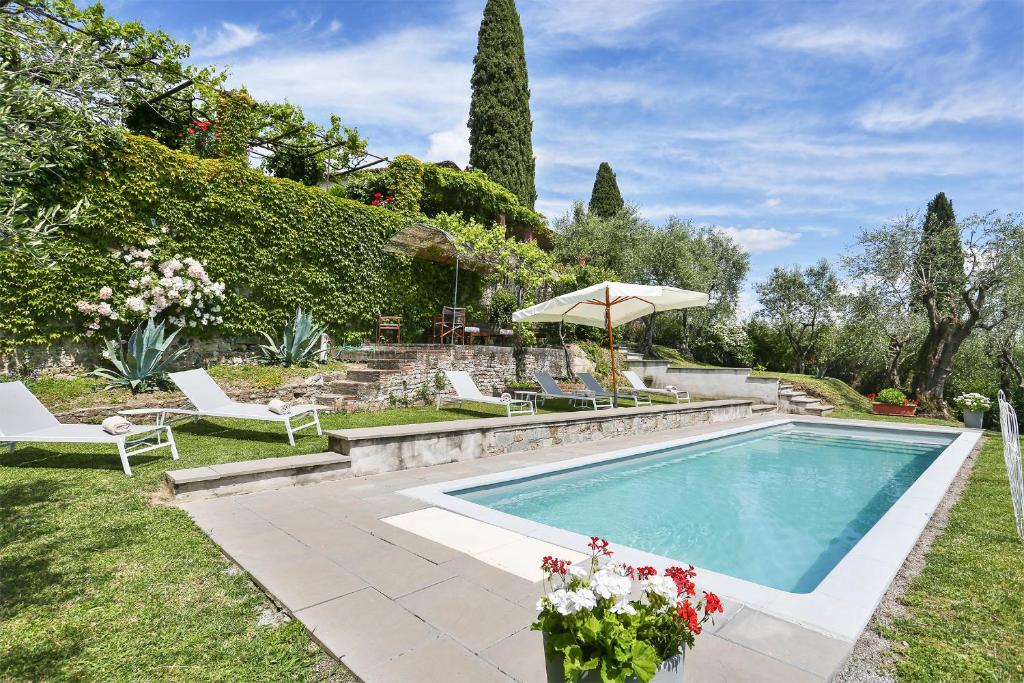 una piscina in un cortile con sedie e ombrellone di Villa Le Cipresse a San Quirico di Moriano