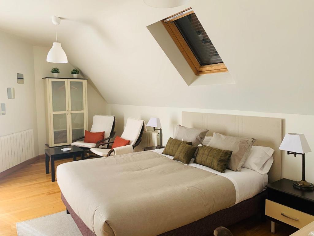 1 dormitorio con 1 cama grande y algunas sillas en Aticos La Aliseda by Valdesierra, en Béjar